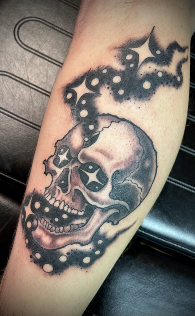 Black and gray skull tattoo cosmic stars